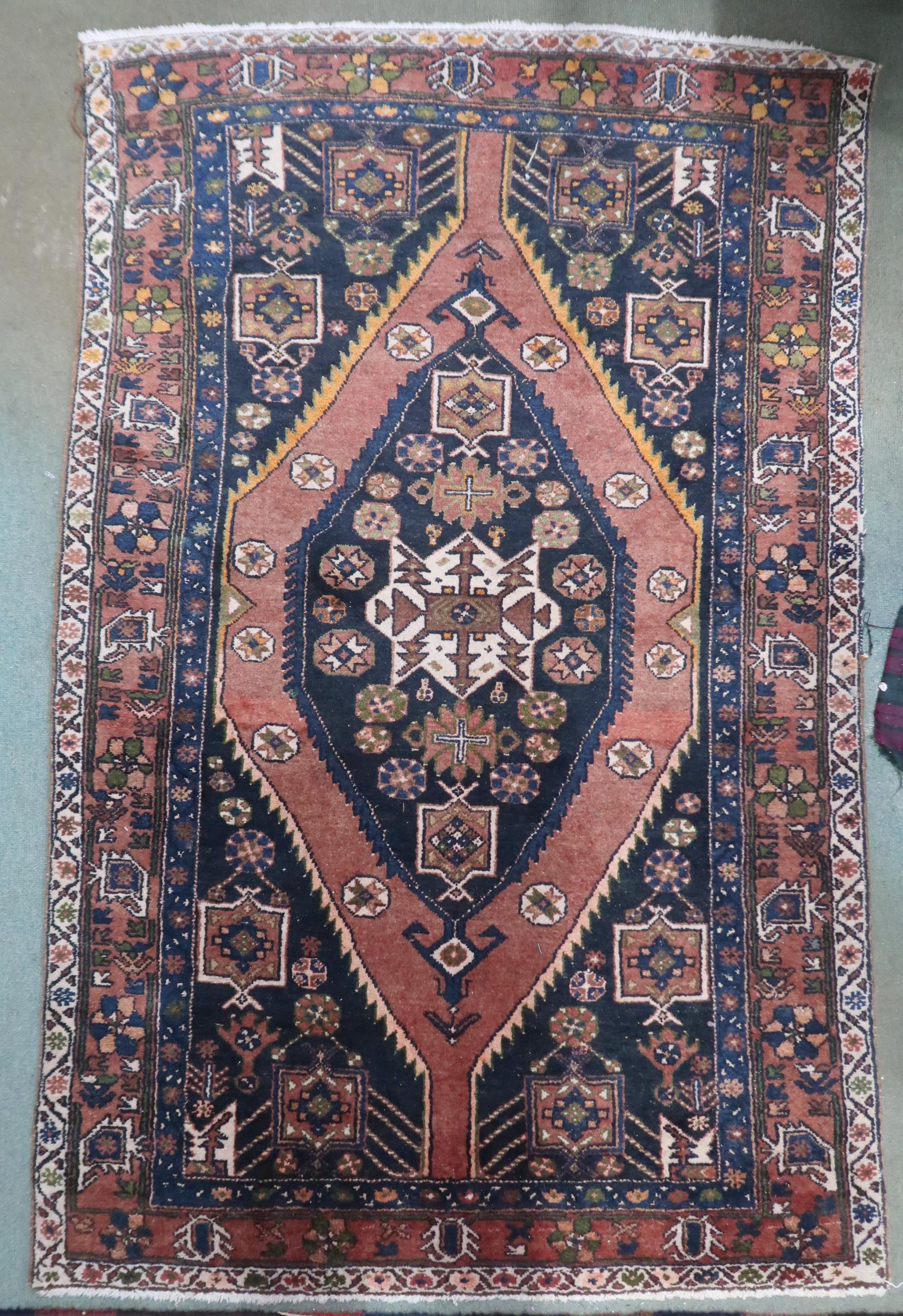 A pink ground balouchi rug with blue diamond central medallion, matching spandrels and pink