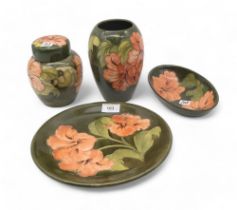 A collection of Moorcroft Hibiscus pattern wares including a charger, a ginger jar, a vase and an