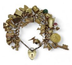 A 9ct gold extensive charm bracelet, with twenty-nine attached charms to include a 1912 gold full