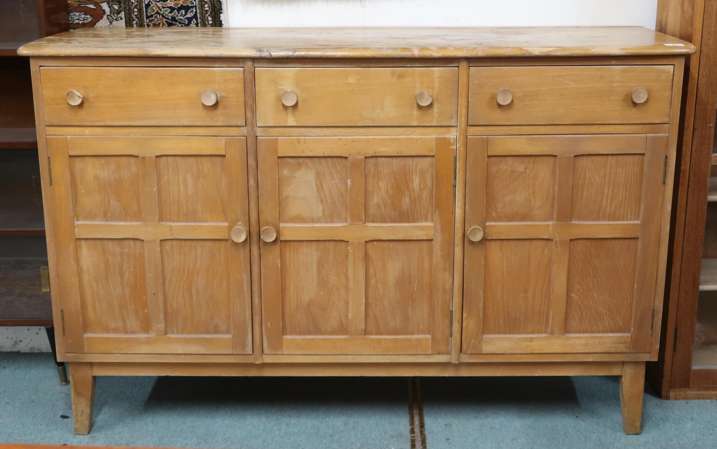 A mid 20th century elm and beech Ercol style sideboard with shaped top over three short drawers over