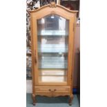 A contemporary oak continental style glazed display cabinet with arched corniced top over glazed