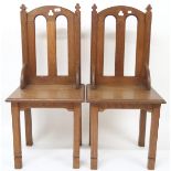 A pair of early 20th century oak ecclesiastical style chairs with pierced trefoil decorations on