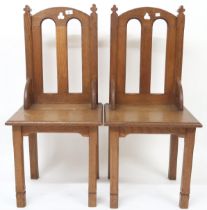 A pair of early 20th century oak ecclesiastical style chairs with pierced trefoil decorations on