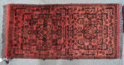 A terracotta ground Persian rug with twinned geometric medallion design within narrow border,