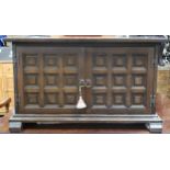 A contemporary stained teak baronial style two door side cabinet on sledge feet, 60cm high x 102cm