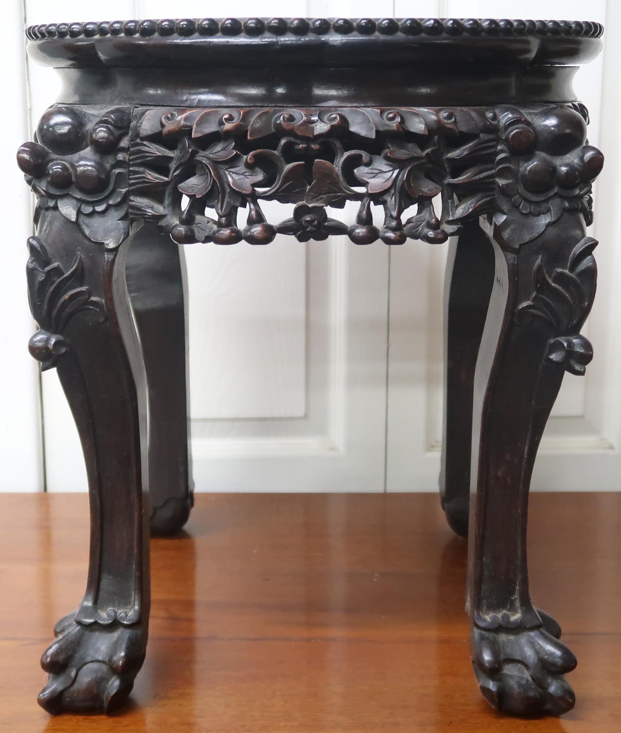 A Chinese hardwood jardinière stand with marble inset top over pierced friezes on carved ball and
