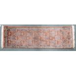 A terracotta ground "100% silk" Kashmir runner with multicoloured geometric design within narrow