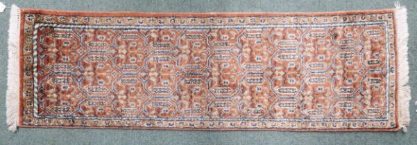 A terracotta ground "100% silk" Kashmir runner with multicoloured geometric design within narrow