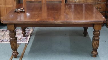A Victorian mahogany wind out extending dining table on turned supports with two spare leaves,