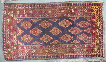 A dark blue ground Iranian Turkman rug with all over lozenge patterned ground within multicoloured
