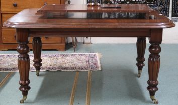 A Victorian mahogany wind-out extending dining table with one spare leaf on turned supports