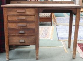 An early 20th century oak G.R.V stamped writing desk with five graduating drawers on square tapering