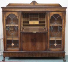An early 20th century oak bureau bookcase with central panel fall front writing compartment over