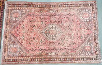 A pink ground Persian Qashqai rug with dark geometric central medallion and matching spandrels on