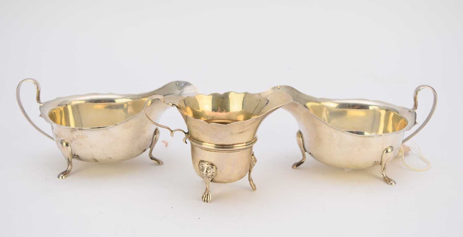 A pair of silver sauce boats and a silver cream jug