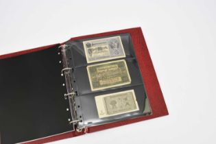 Red album containing 20 world banknotes