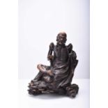 A Chinese carved wood figure of a seated Luohan, Qing Dynasty