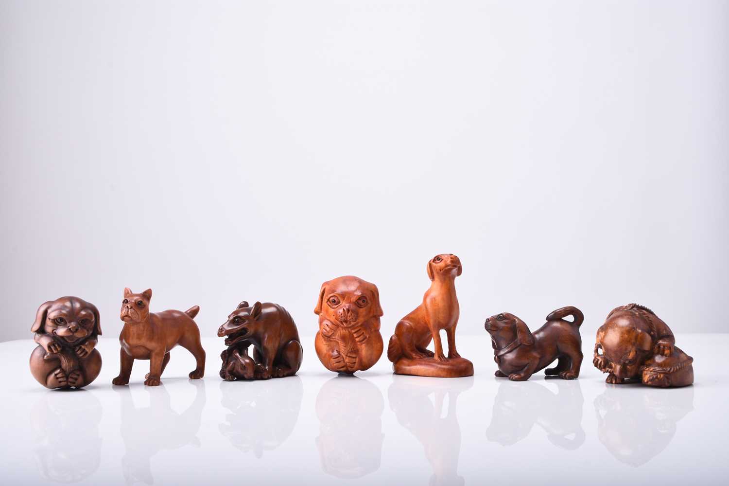 A group of seven Japanese wood netsuke of dogs and puppies, 20th century