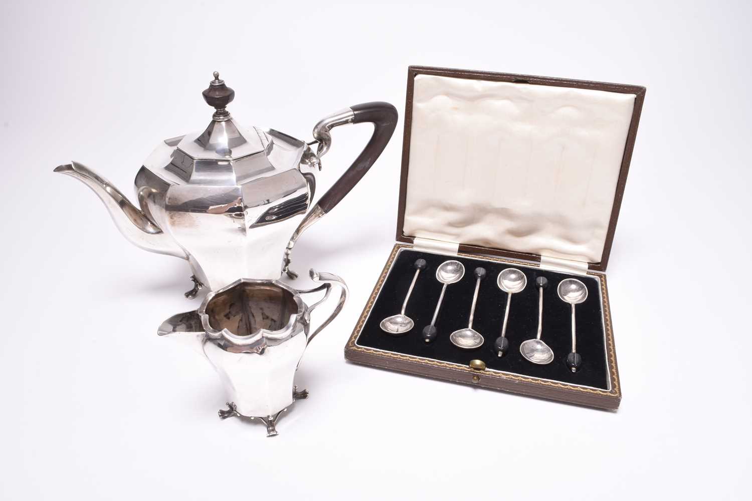 A silver teapot and cream jug and a cased set of six coffee spoons