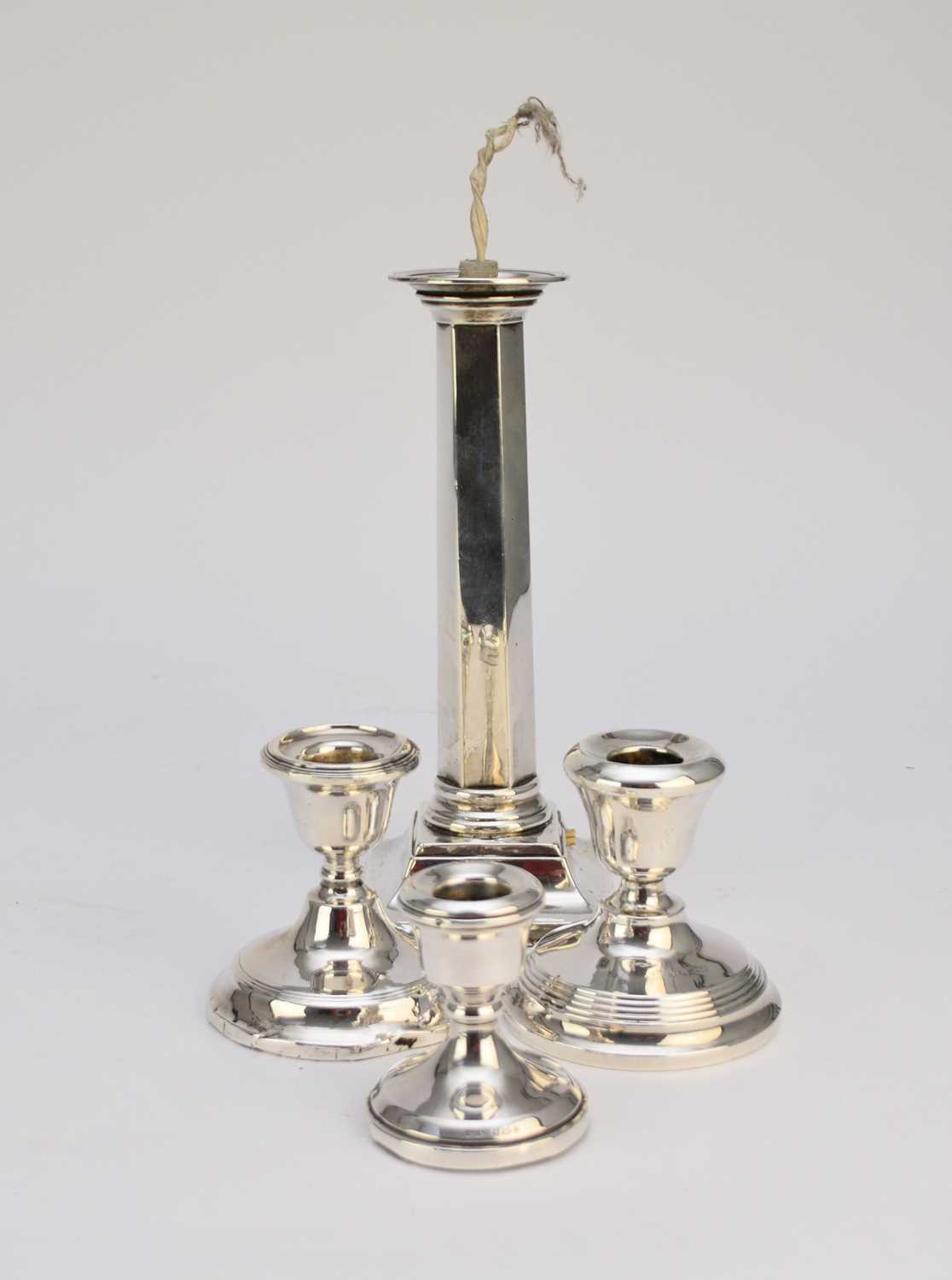 A silver mounted lamp base and three candlesticks