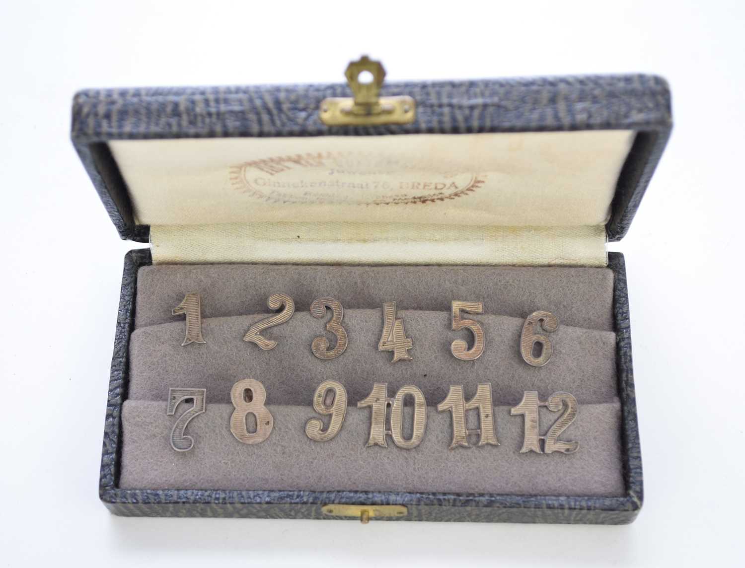 A cased set of white metal numbers