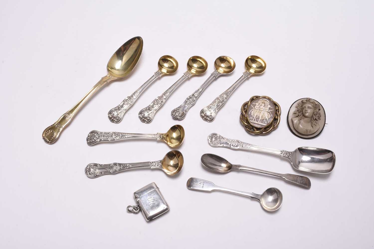 A collection of silver flatware, a silver vesta case and two brooches