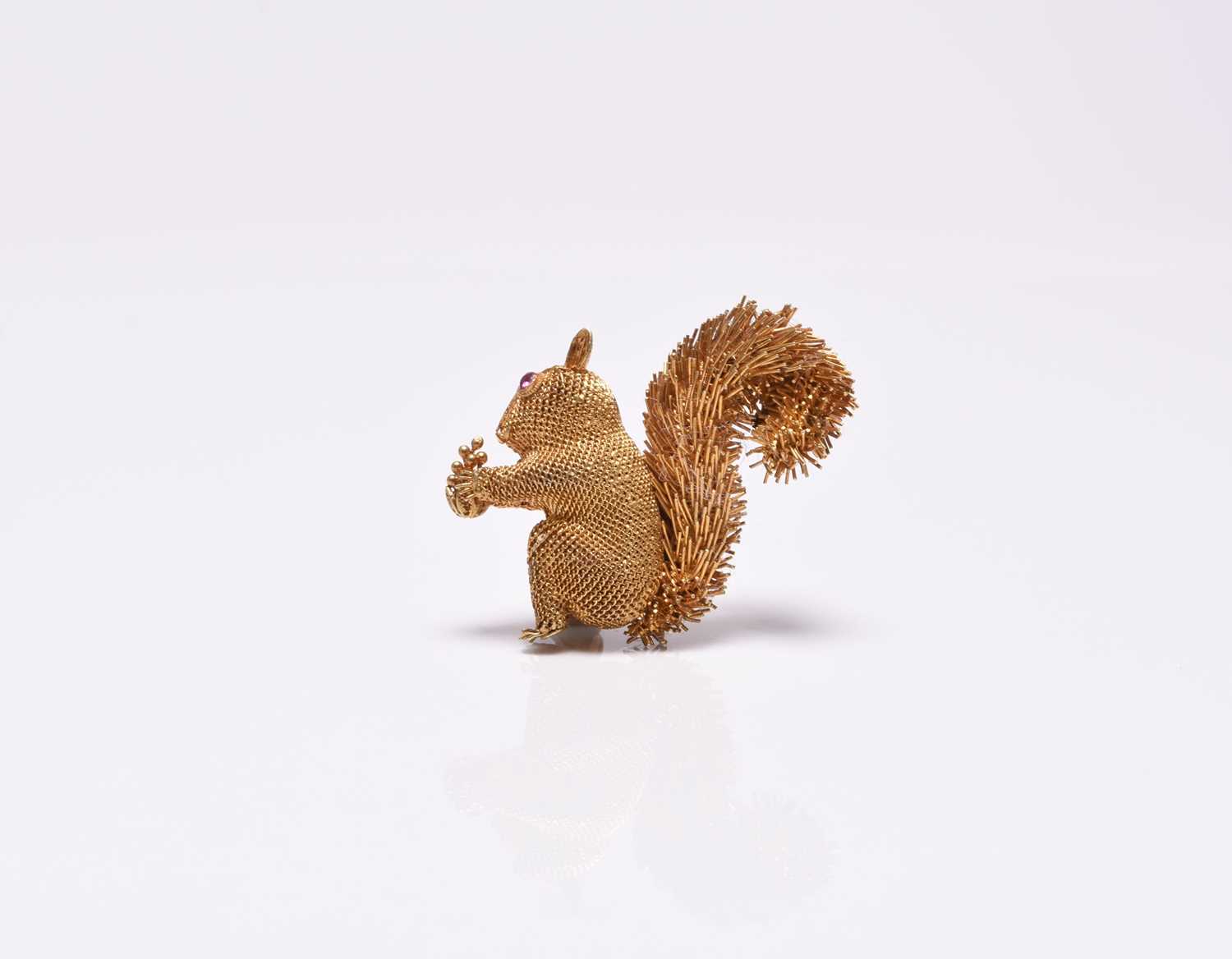 A yellow metal squirrel brooch