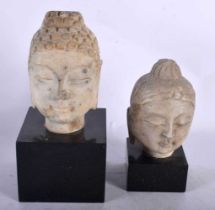 TWO CHINESE QING DYNASTY CARVED STONE HEADS OF BUDDHA modelled with sureen expressions. Largest 23