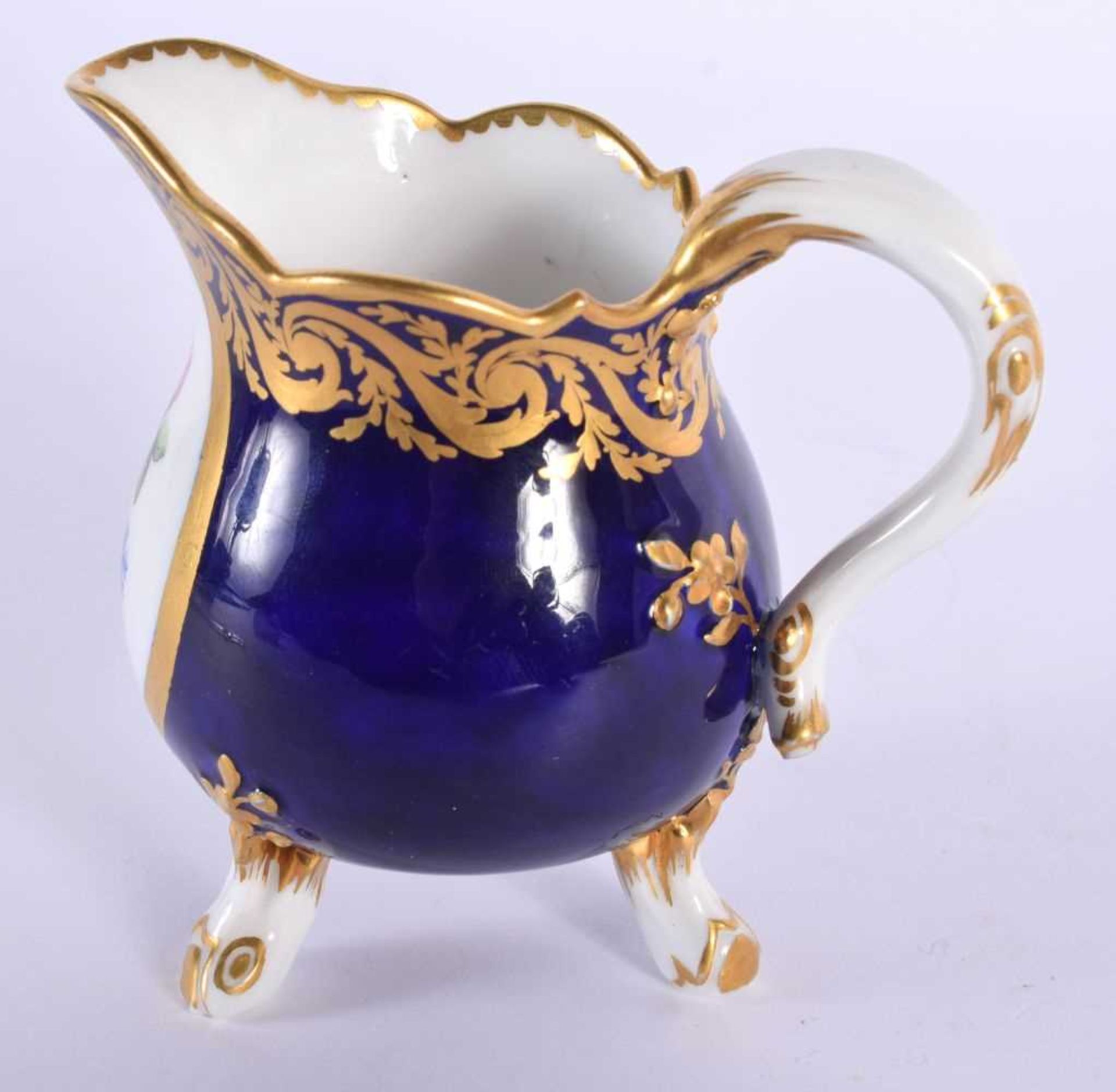 Sevres cream jug on three feet painted with flowers in a tear-drop panel, the cobalt blue ground