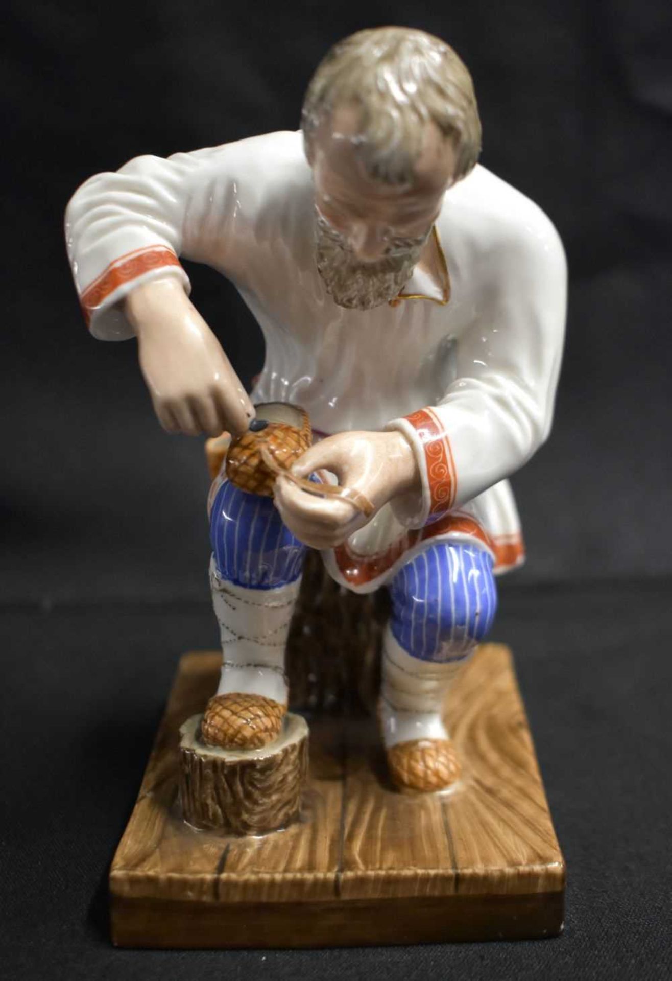 A LATE 19TH CENTURY RUSSIA ST PETERSBURG PORCELAIN FIGURE OF A COBBLER modelled repairing a shoe. 14