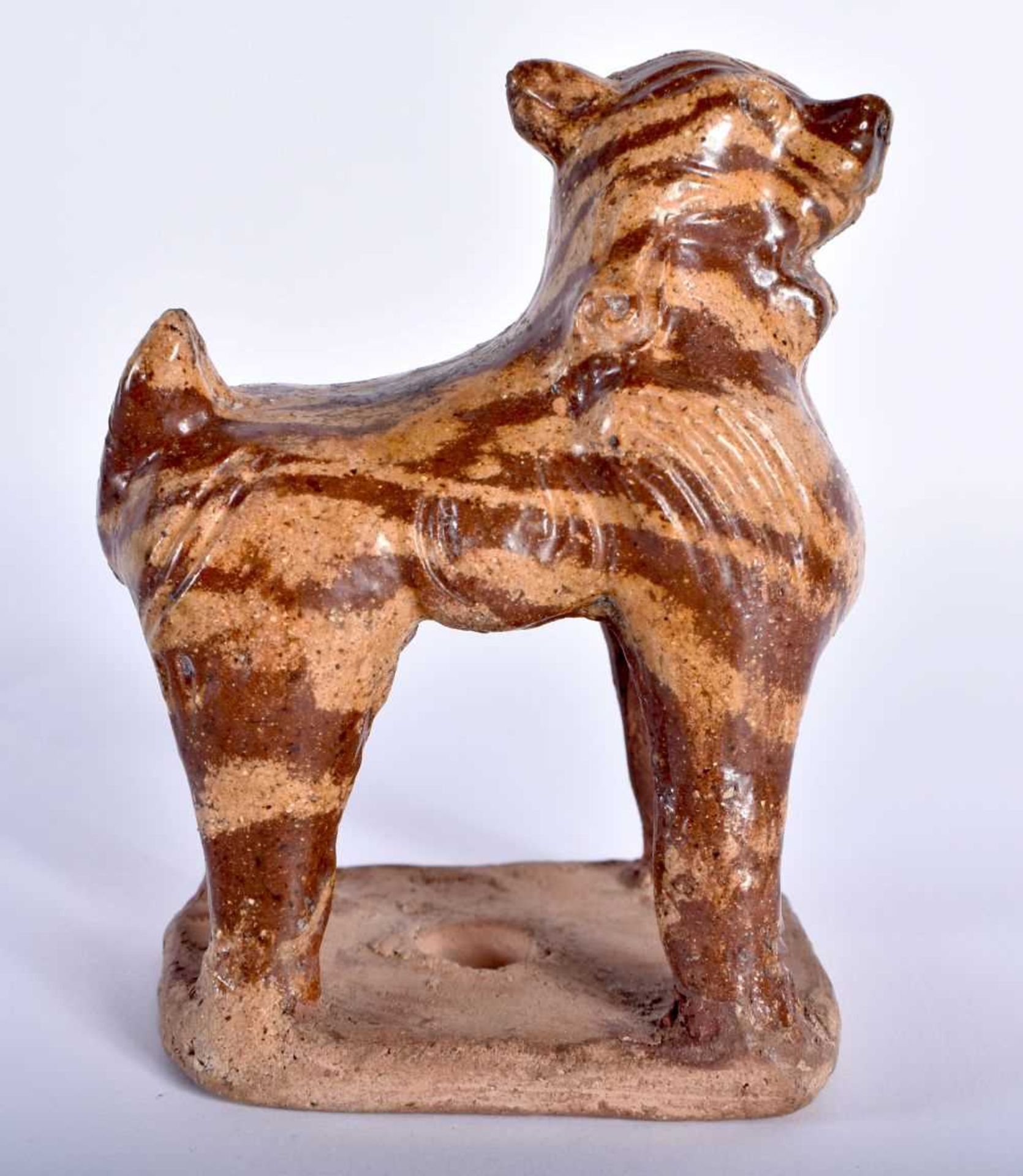 AN EARLY CHINESE MARBLEISED POTTERY BEAST modelled standing upon an unglazed base. 11 cm x 8 cm.