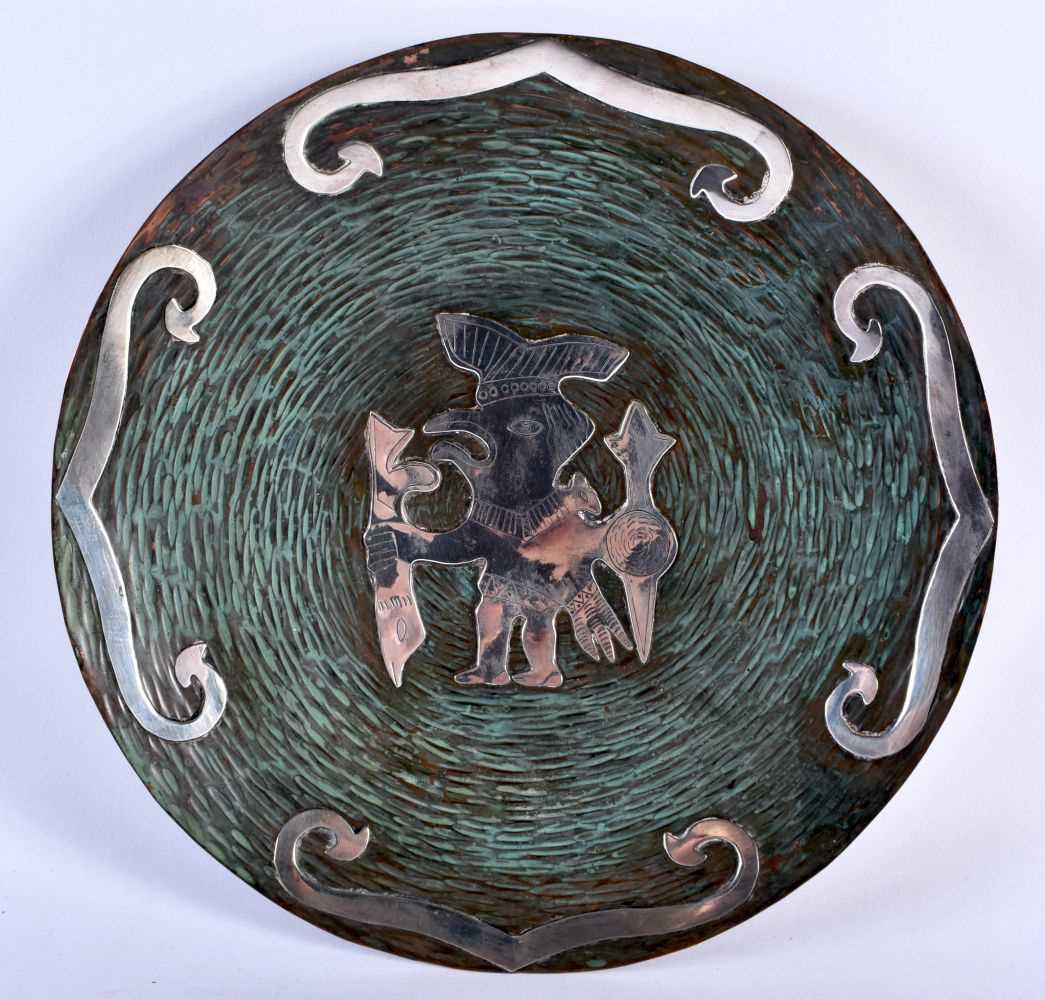 A VINTAGE PERUVIAN SILVER OVERLAID 60627 PLATE depicting a tribal figures. 24 cm diameter.