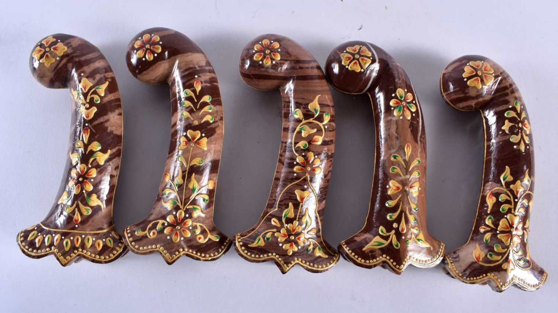 A SET OF FIVE MIDDLE EASTERN QAJAR LACQUER HARDSTONE DAGGER HANDLES overlaid with foliage and vines.