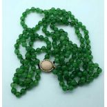 A Jade Necklace with an 18 Caral Gold Clasp set with Diamonds. Stamped 18K and 750. Length 53cm.