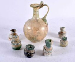 A ROMAN GLASS JUG together with six smaller glass vessels. Largest 12.5 cm high. (7)