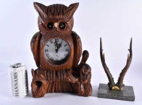 A LARGE BLACK FOREST BAVARIAN OWL CLOCK together with a pair of antlers. Largest 34 cm x 18 cm. (2)