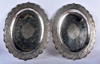 A LARGE PAIR OF 19TH CENTURY INDIAN SILVER REPOUSSE SERVING TRAYS decorated with foliage and
