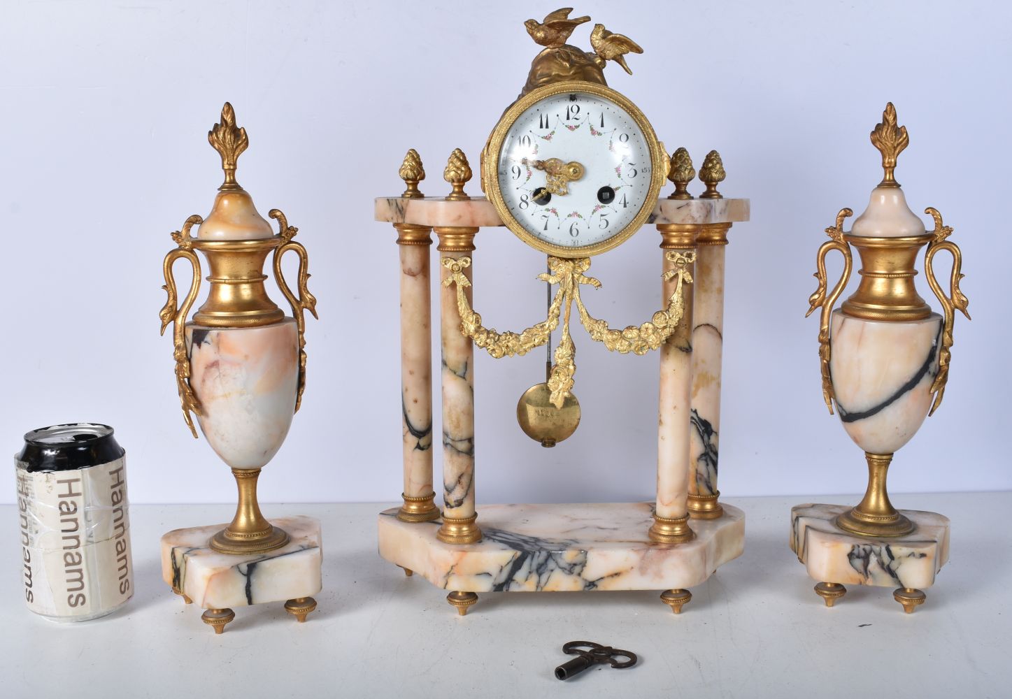 An early 20th Century French gilt metal and marble Clock set with a metal enamelled clock face