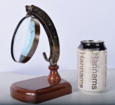A bronzed adjustable magnifying glass on a wooden stand 21 x 12 cm