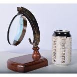 A bronzed adjustable magnifying glass on a wooden stand 21 x 12 cm