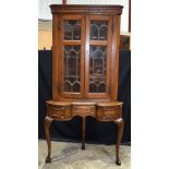 An Oak glazed door corner cabinet on a a stand with one central drawer and 2 front opening small