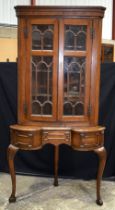 An Oak glazed door corner cabinet on a a stand with one central drawer and 2 front opening small