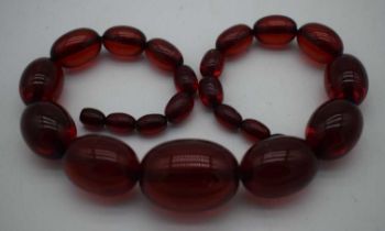 A LARGE CHERRY AMBER TYPE NECKLACE. 77 grams. 45cm long, largest bead 3.5 cm x 2.5 cm.