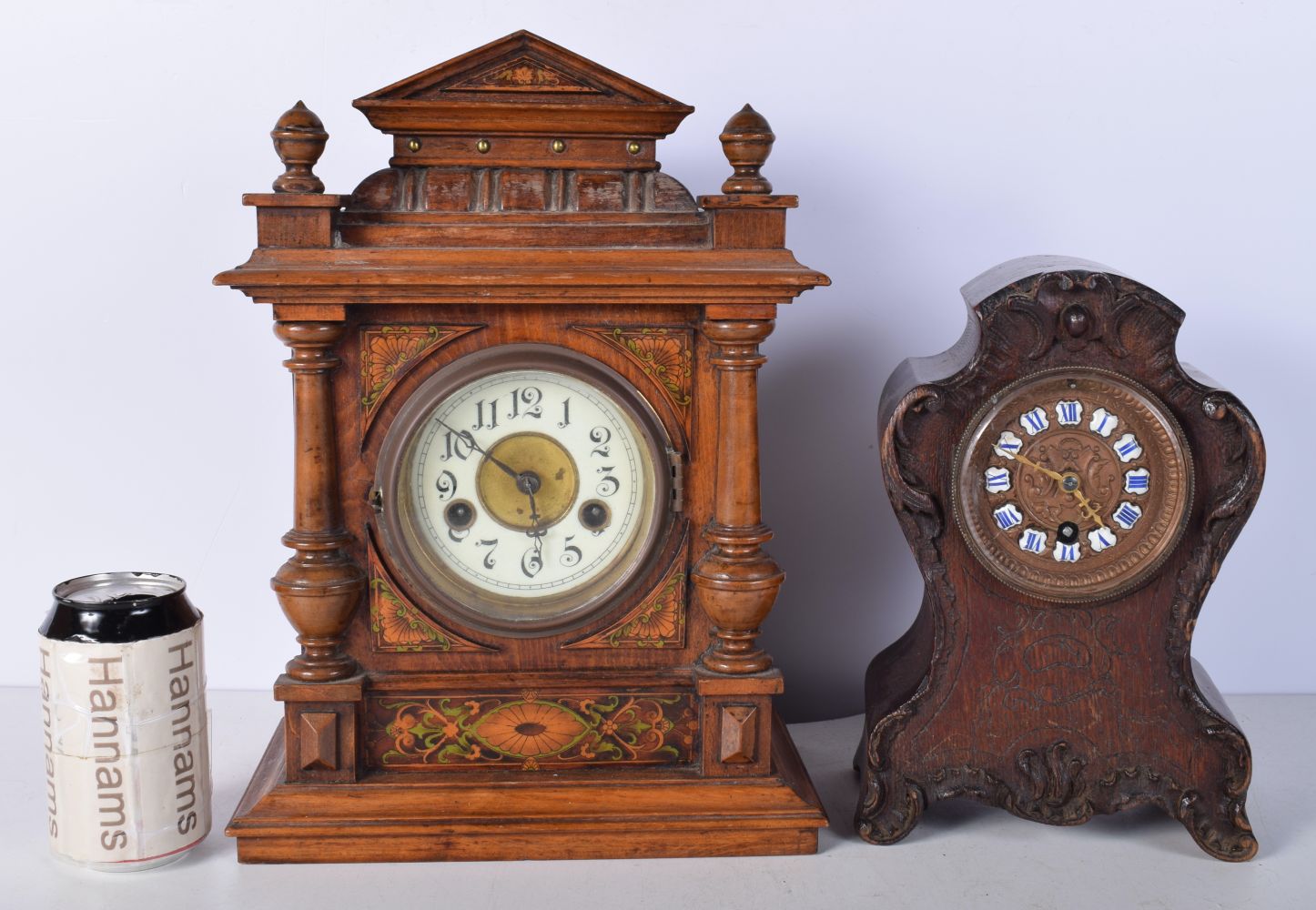 An antique wooden inlaid mantle clock with a porcelain face together with a carved Oak mantle clock