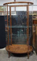 A large mahogany Edwardian bow fronted glass display cabinet with glass shelves and a wooden