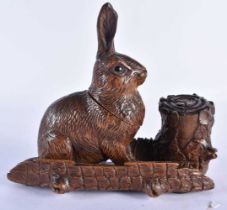 A 19TH CENTURY BAVARIAN BLACK FOREST CARVED WOOD INKWELL formed as a seated rabbit beside a well.