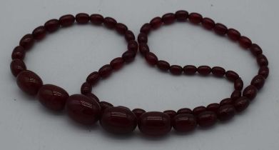 A CHERRY AMBER NECKLACE. 54 grams. 76 cm long, largest bead 2.5 cm x 1.75 cm.