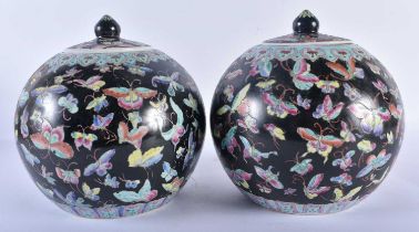 A PAIR OF CHINESE FAMILLE NOIRE PORCELAIN GINGER JARS AND COVERS painted with butterflies and vines.