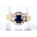 An 18 Carat Gold Ring Set with a Sapphire surrounded by Diamonds. Hallmarked Birmingham 1975, Size