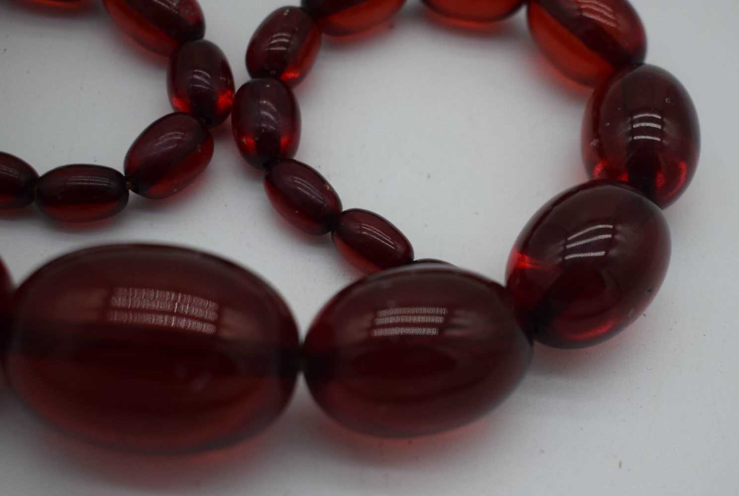 A LARGE CHERRY AMBER TYPE NECKLACE. 77 grams. 45cm long, largest bead 3.5 cm x 2.5 cm. - Image 3 of 3